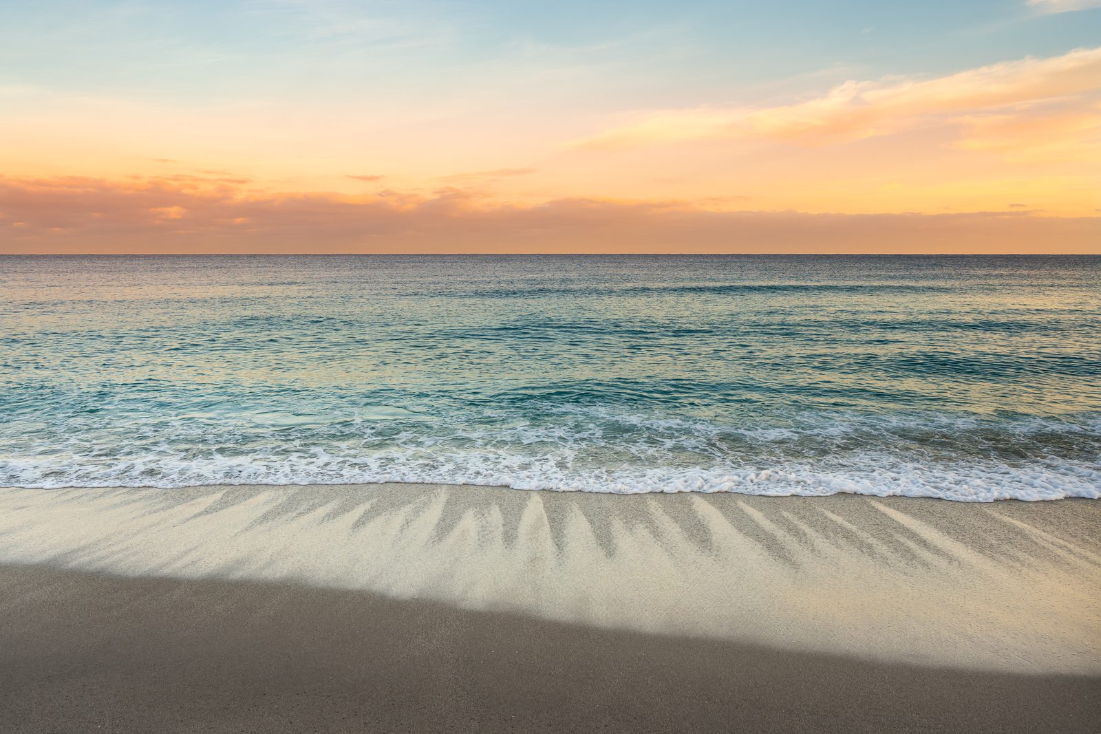 Gentle waves meeting a quiet South Florida beach at sunset